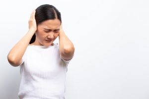 Sad woman covering her ears standing isolated over white background