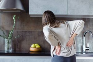 woman in kitchen holding back in pain